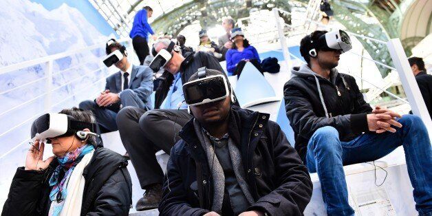 Visitors test virtual reality headsets at the 'Solutions COP21' exhibition at the Grand Palais in Paris on December 4, 2015 on the sidelines of the COP21 United Nations conference on climate change. / AFP / LOIC VENANCE (Photo credit should read LOIC VENANCE/AFP/Getty Images)