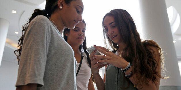 In this July 27, 2015, photo, Giulia Pugliese, 15, right, posts a picture to Snapchat while her friend Isabella Cimato, 17, left, and her cousin Arianna Schaden, 14, look on at Roosevelt Field shopping mall in Garden City, N.Y. Teens arent roaming around at the mall for kicks during back-to-school. Theyre researching the looks they want online and follow popular hashtags on social media so they can piece together looks before they get there. (AP Photo/Seth Wenig)