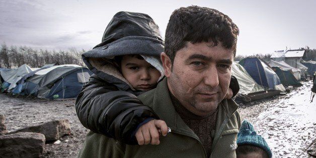 TOPSHOT - A man and his children from Iraq poses in the so-called 'Jungle' migrant camp in Gande-Synthe where 2,500 refugees from Kurdistan, Iraq and Syria live on February 11, 2016 in Grande-Synthe near the city of Dunkirk, northern France. / AFP / PHILIPPE HUGUEN (Photo credit should read PHILIPPE HUGUEN/AFP/Getty Images)
