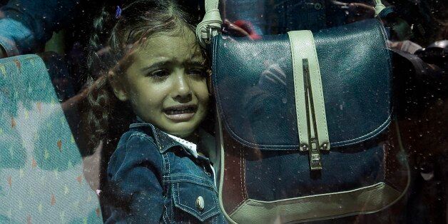 A girl cries as she waits on a bus which will transport her family to the metro station, after their arrival from the northeastern Greek island of Lesbos to the Athens' port of Piraeus on Tuesday, Sept. 8, 2015. About 2,500 refugees and migrants arrived with the ferry Eleftherios Venizelos as Frontex, the EU border agency, says more than 340,000 asylum seekers have entered the 28-nation bloc this year, the majority fleeing war and human rights abuses in Syria, Afghanistan, Iraq, Somalia and Eritrea. (AP Photo/Thanassis Stavrakis)