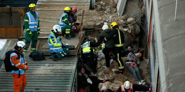 Evaluators on the roof of a container watch to see how members of the emergency services treat simulated casualties during an exercise run by the London Fire Brigade at a disused power station in east London, Monday, Feb. 29, 2016. The exercise involving the London emergency services is set around a building collapse onto a major London underground railway station. (AP Photo/Alastair Grant)