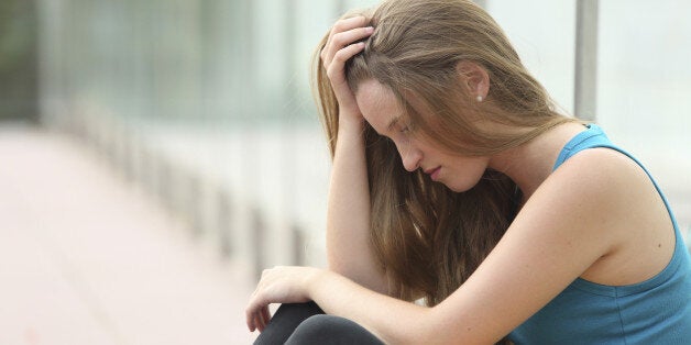 Teenager girl sitting on the floor outdoor depressed with a hand in the head