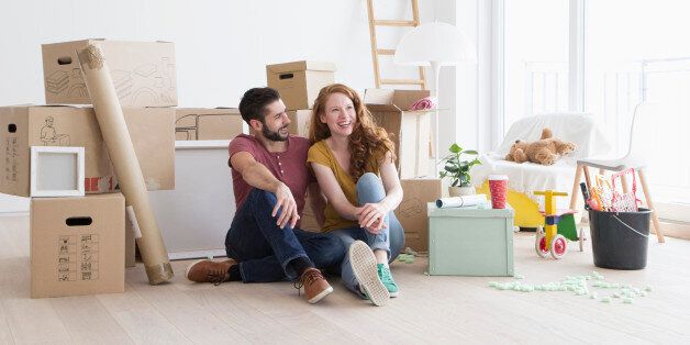 Young couple in new flat with cardboard boxes, sitting on floor
