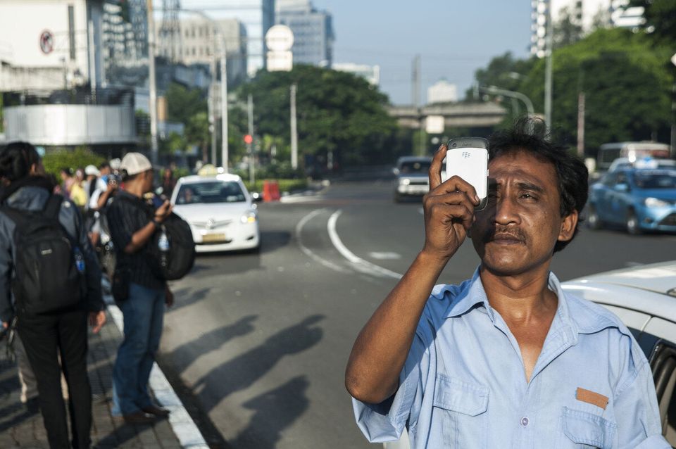 JAKARTA, INDONESIA - MARCH 08 : An Indonesian Man take picture a solar eclipse without goggles in Jakarta, Indonesia, Wednesday, March 9, 2016. The rare astronomical event is being witnessed Wednesday along a narrow path that stretches across 12 province