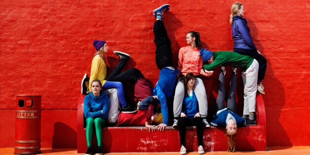 Young people sitting and lying on each other on a red bench.