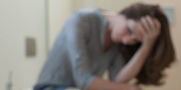 Unhappy woman in bathroom with pregnancy test