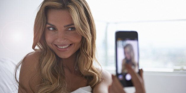 Stock image: Young woman taking selfie with cameraphone.