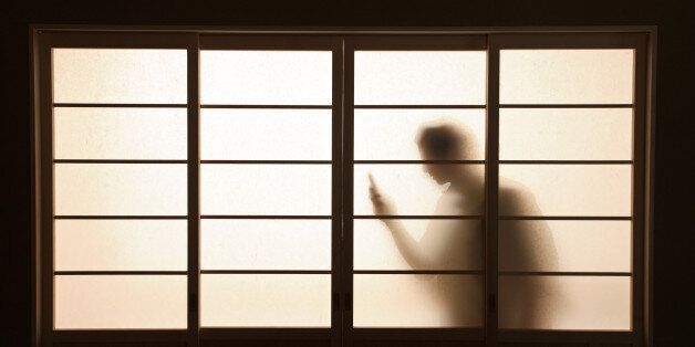 figure holding phone silhouetted behind screen