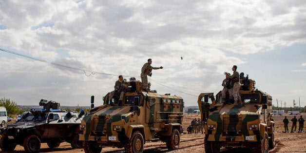 Turkish solders in military vehichles observe the street to the border with Syria in Suruc September 28, 2014 south of Sanliurfa, Turkey. Islamic State (IS, also called ISIS and ISIL) fighters are reportedly advancing with heavy weaponry on the strategic Kurdish border town of Kobani (also called Ayn Al-Arab), which they have surrounded on three sides