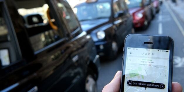 A man holds a smartphone displaying the Uber app as taxis line up on Fleet Street during a protest by the United Cabbies Group (UCG), which represents more than 1,400 London black cab drivers, over the regulation of private hire cars.