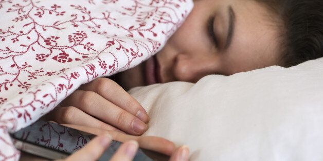 Woman sleeping in bed with smartphone in hand