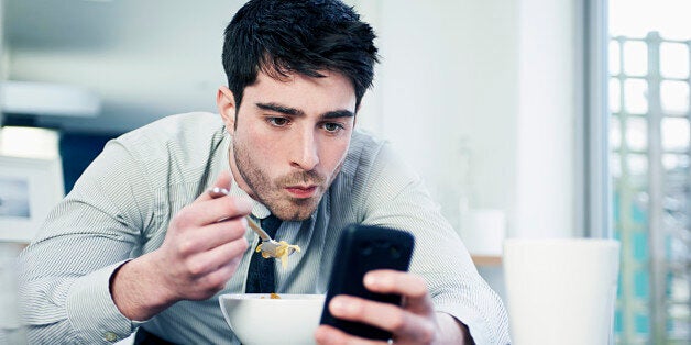 business man eating breakfast with mobile