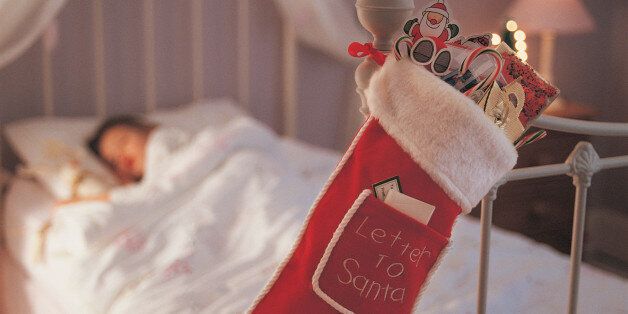 Christmas Stocking Hanging on a Bed Knob and a Child Sleeping in Bed in the Background