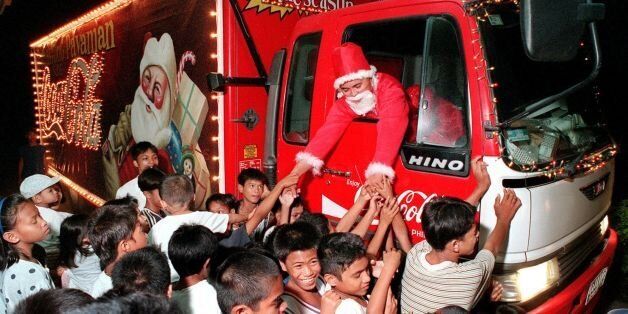 BACOLOD, PHILIPPINES - DECEMBER 4: A local Coca Cola salesman dressed as Santa Claus riding a specially decorated delivery truck visits an orphanage in Bacolod city in central Philippines, 04 December 1999, where he distributed gifts to the ophans bringing cheers in the spirit of the Christmas season. (Photo credit should read MARCIAL ANGELO/AFP/Getty Images)
