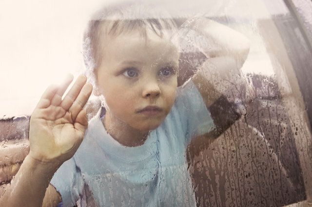 Boy looking out rain-streaked car window