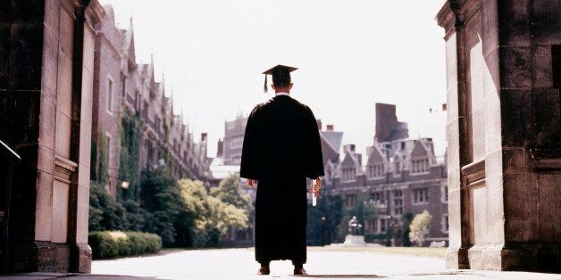 1960s BACK VIEW MALE GRADUATE WEARING CAP AND GOWN STANDING IN CAMPUS ARCHWAY UNIVERSITY OF PENNSYLVANIA PHILADELPHIA USA (Photo by H. Armstrong Roberts/ClassicStock/Getty Images)