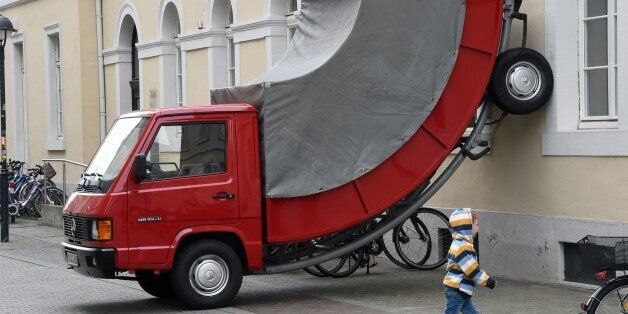 A child walks past the work 'Truck' by Austrian artist Erwin Wurm on June 21, 2015 in Karlsruhe, southwestern Germany. The work is part of the exhibition 'The City is the Star Art at the Construction Site' running across the city until September 27, 2015. AFP PHOTO / DPA / ULI DECK +++ GERMANY OUYRESTRICTED TO EDITORIAL USE, MANDATORY MENTION OF THE ARTIST UPON PUBLICATION, TO ILLUSTRATE THE EVENT AS SPECIFIED IN THE CAPTION (Photo credit should read ULI DECK/AFP/Getty Images)