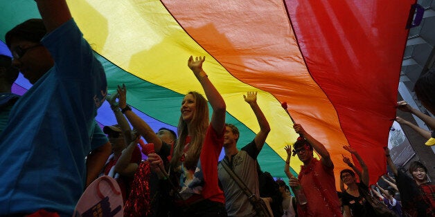 Participants march as they walk under a rainbow flag, a symbol of the gay rights movement, during a gay rally in Hong Kong Saturday, Nov. 9, 2013. Organizers say thousands of people are taking part in the annual Gay Pride Parade including representatives from more than 50 organizations as well as participants from the mainland and Taiwan, according to government radio. (AP Photo/Vincent Yu)