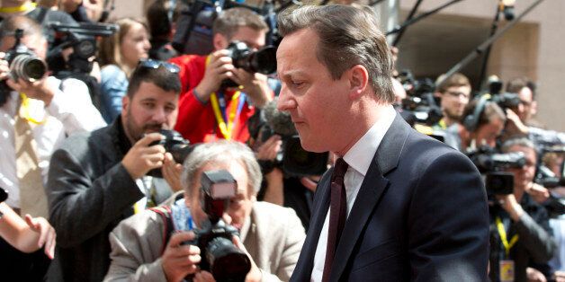 British Prime Minister David Cameron walks by the media as he arrives for an EU summit in Brussels