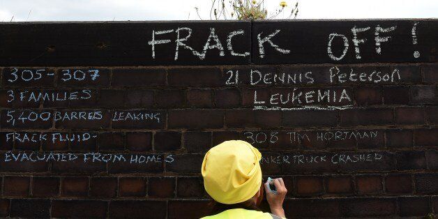 An anti-fracking demonstrator writes messages on a wall outside Lancashire County Hall in Preston, northwest England, on June 23, 2015 during a demonstration to protest against the applications from energy firm Cuadrilla to start two fracking operations on nearby sites. Lancashire County Council were expected to vote on June 24 on of one of two applications from energy firm Cuadrilla to start fracking operations at the nearby Little Plumpton and Roseacre Wood sites. Fracking or hydraulic fracturing is a process used to extract shale gas by blasting a high-pressure mixture of water, sand and chemicals deep underground to release hydrocarbons trapped between layers of rock. AFP PHOTO / PAUL ELLIS (Photo credit should read PAUL ELLIS/AFP/Getty Images)
