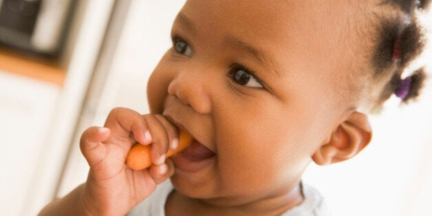 Young girl eating carrot indoors