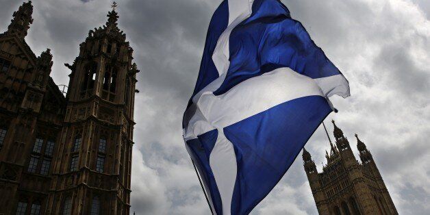 A member of public flies a giant Scottish Saltire flag outside the Houses of Parliament