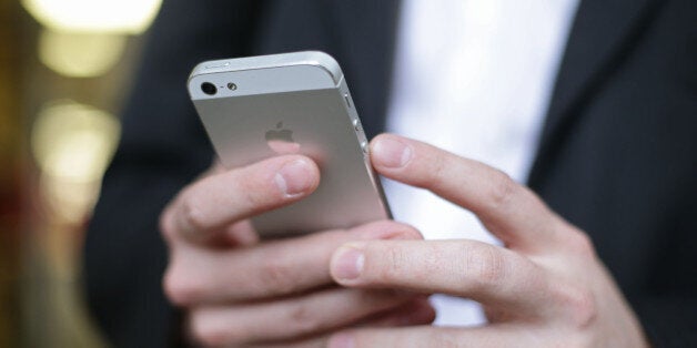 A man using an iPhone outside the Apple Store in Covent Garden, London. The technology giant has smashed the global record for quarterly profits after racking up a surplus of 18 billion US dollars (£11.9 billion).