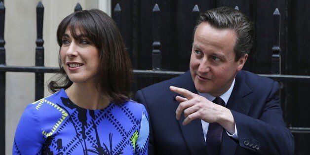 Britain's Prime Minister David Cameron gestures as he walks with his wife Samantha in Downing Street in London Friday, May 8, 2015. Cameron's Conservative Party swept to power Friday in Britain's Parliamentary elections winning an unexpected majority. (AP Photo/Alastair Grant )