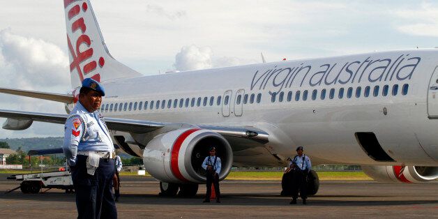 Indonesian Air Force personnel stand guard by a Virgin Australia airplane in Bali, Indonesia, Friday, April 25, 2014. A drunken passenger who caused a hijack scare on a Virgin Australia flight by trying to break into the cockpit was arrested Friday after the plane landed on Indonesia's resort island of Bali, officials said. (AP Photo/Firdia Lisnawati)