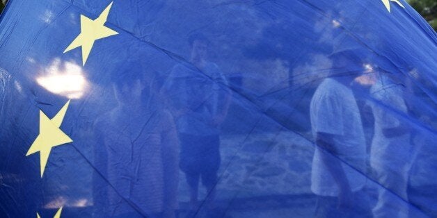 Pro-Euro demonstrators are seen behind a European Union flag during a rally in the northern Greek port city of Thessaloniki, Thursday, July 9, 2015. Hopes that Greece can get a rescue deal that will prevent a catastrophic exit from the euro rose on Thursday, after key creditors said they were open to discussing how to ease the country's debt load, a long-time sticking point in their talks. (AP Photo/Giannis Papanikos)