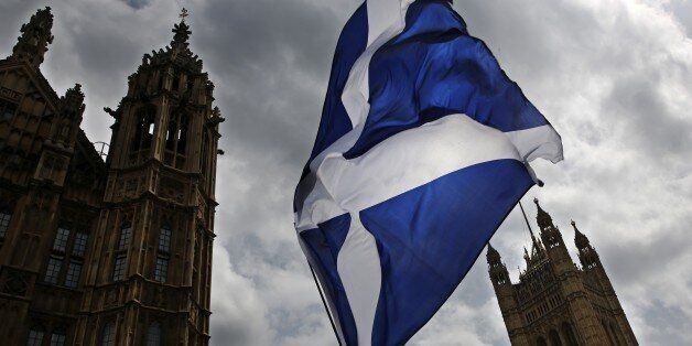 A member of public flies a giant Scottish Saltire flag outside the Houses of Parliament shortly before Scotland First Minister Nicola Sturgeon posed with newly-elected Scottish National Party (SNP) MPs during a photocall in London on May 11, 2015. The SNP won a landslide in Scotland in the May 7 general election, destroying the Labour party north of the border in a historic leap forward which could increase pressure for a fresh referendum on independence. The nationalists won 56 of 59 parliament