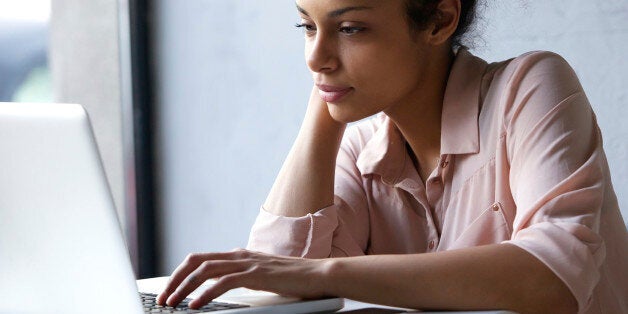 Close up portrait of a young black woman looking at laptop