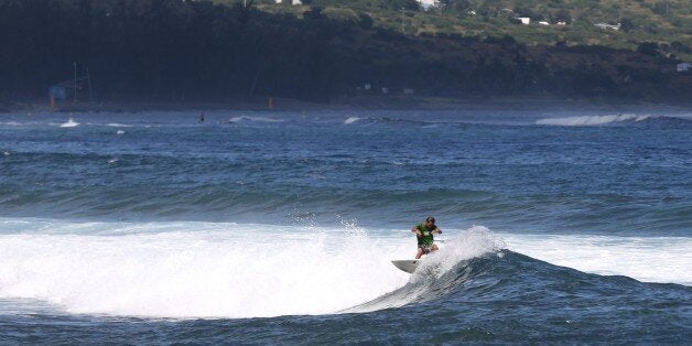 A surfer rides a wave, on April 14, 2015 off Saint-Leu, on the western coast of the French Indian Ocean island of La Reunion, two days after a 13-year-old boy was attacked and killed by a shark. It was the 16th shark attack on the island since 2011 and the seventh loss of life. AFP PHOTO / RICHARD BOUHET (Photo credit should read RICHARD BOUHET/AFP/Getty Images)