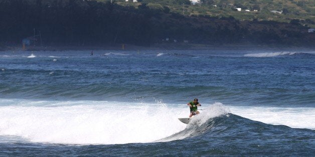 A surfer rides a wave, on April 14, 2015 off Saint-Leu, on the western coast of the French Indian Ocean island of La Reunion, two days after a 13-year-old boy was attacked and killed by a shark. It was the 16th shark attack on the island since 2011 and the seventh loss of life. AFP PHOTO / RICHARD BOUHET (Photo credit should read RICHARD BOUHET/AFP/Getty Images)