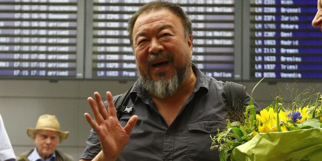 Chinese dissident artist Ai Weiwei answers to questions of journalists after his arrival at the airport in Munich, Germany, Thursday, July 30, 2015. Ai Weiwei is on his way to Berlin where part of his family lives. Standing at right is Bavarian Green politician Margarethe Bause. (AP Photo/Matthias Schrader)