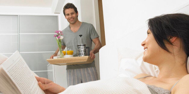 Man bringing 'breakfast in bed' to woman, smiling