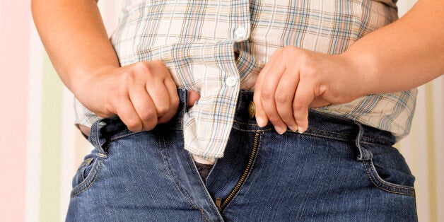 Obese teenager squeezing into a pair of too tight jeans.