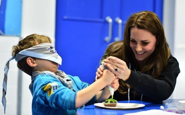 The Duchess of Cambridge helps blindfolded Fynley Gooch, aged seven, ice a cake as she promotes disability awareness when she met with children at the newly established 23rd Poplar Beaver Scout Colony in east London. PRESS ASSOCIATION Photo. Picture date: Tuesday December 16, 2014. Kateâs visit supports the Scout Association's 'Better Prepared' campaign, which aims to help communities to deliver Scouting to two hundred locations across the UK where Scouting can have the biggest impact. Photo credit should read: Ben Stansall/PA Wire