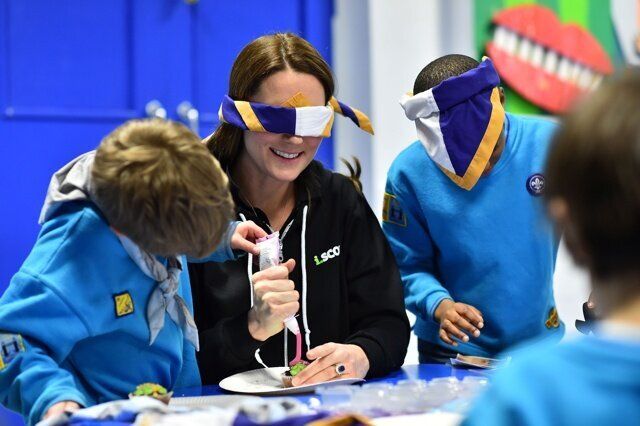 The Duchess of Cambridge, wearing a blindfold, is helped to ice a cake by Fynley Gooch, aged seven, as she promotes disability awareness when she met with children at the newly established 23rd Poplar Beaver Scout Colony in east London. PRESS ASSOCIATION Photo. Picture date: Tuesday December 16, 2014. Kateâs visit supports the Scout Association's 'Better Prepared' campaign, which aims to help communities to deliver Scouting to two hundred locations across the UK where Scouting can have the biggest impact. Photo credit should read: Ben Stansall/PA Wire