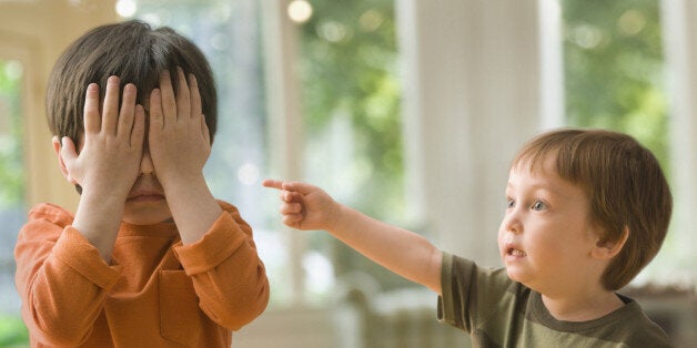 Boy pointing at brother who's covering his eyes