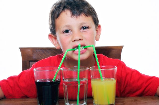 This is an image of a beautiful child drinking three different kind of sodas.