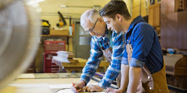 Senior carpenter working with apprentice in workshop