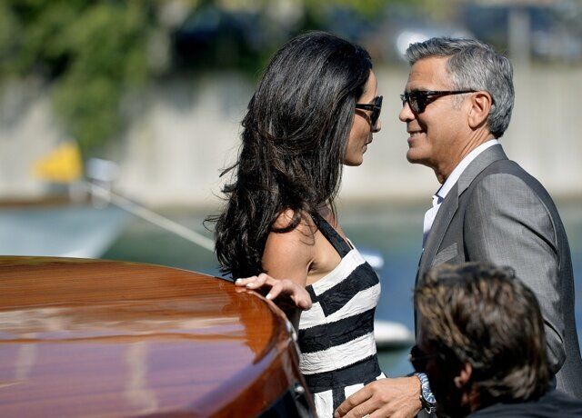 US actor George Clooney (R) and his Lebanon-born British fiancee Amal Alamuddin take a taxiboat upon their arrival in Venice on September 26, 2014, on the eve of their wedding. The party of the year is happening here: the fresco-adorned Aman hotel on Venice's Grand Canal is feverishly preparing for George Clooney's wedding to Amal Alamuddin, his Lebanon-born British fiancee. Hollywood stars and the world's paparazzi have already begun arriving for the nuptials of the world's most sought-after catch, who will, sources said, celebrate with 136 guests at the exclusive seven-star hotel in the 450-year-old Palazzo Papadopoli. AFP PHOTO / ANDREAS SOLARO (Photo credit should read ANDREAS SOLARO/AFP/Getty Images)