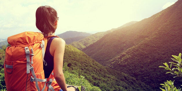 woman backpacker enjoy the view at mountain peak cliff