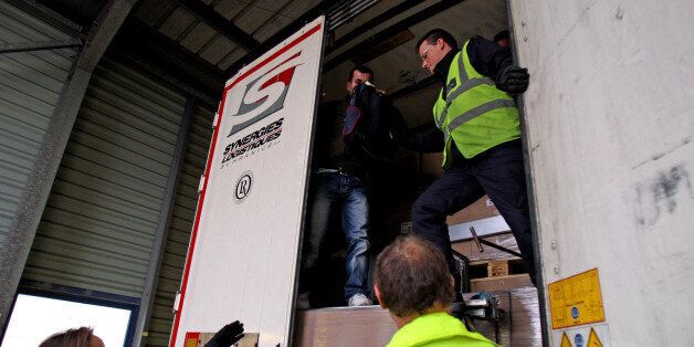 A stowaway passenger climbs down from a lorry trailer helped by UK Border Control after being discovered hiding behind boxes in the back of the trailer at Calais Ferry Port in France.
