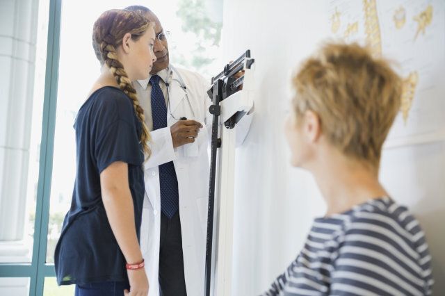 Doctor measuring girls weight in clinic