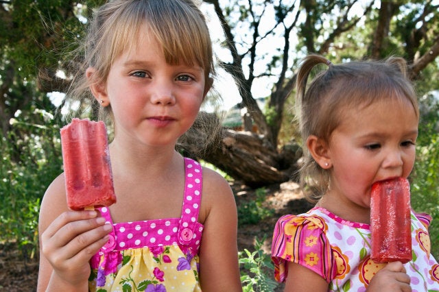 Young girls eating fruit popsicles outdoors