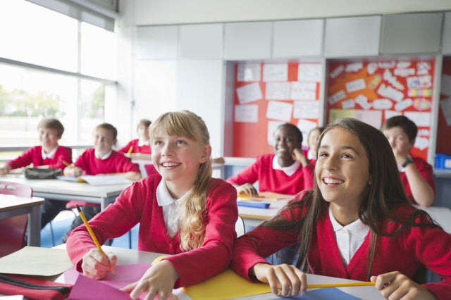 Smiling students writing in classroom