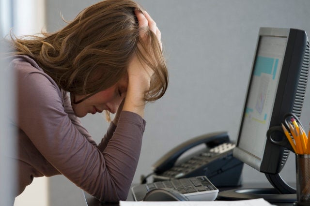 Woman with head buried in hands in office