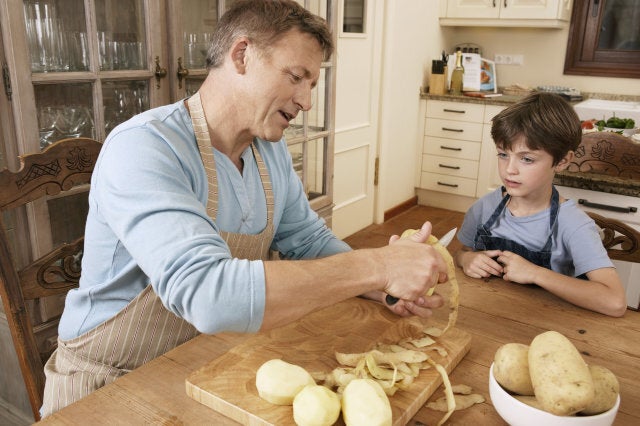 Son watching father peel potato